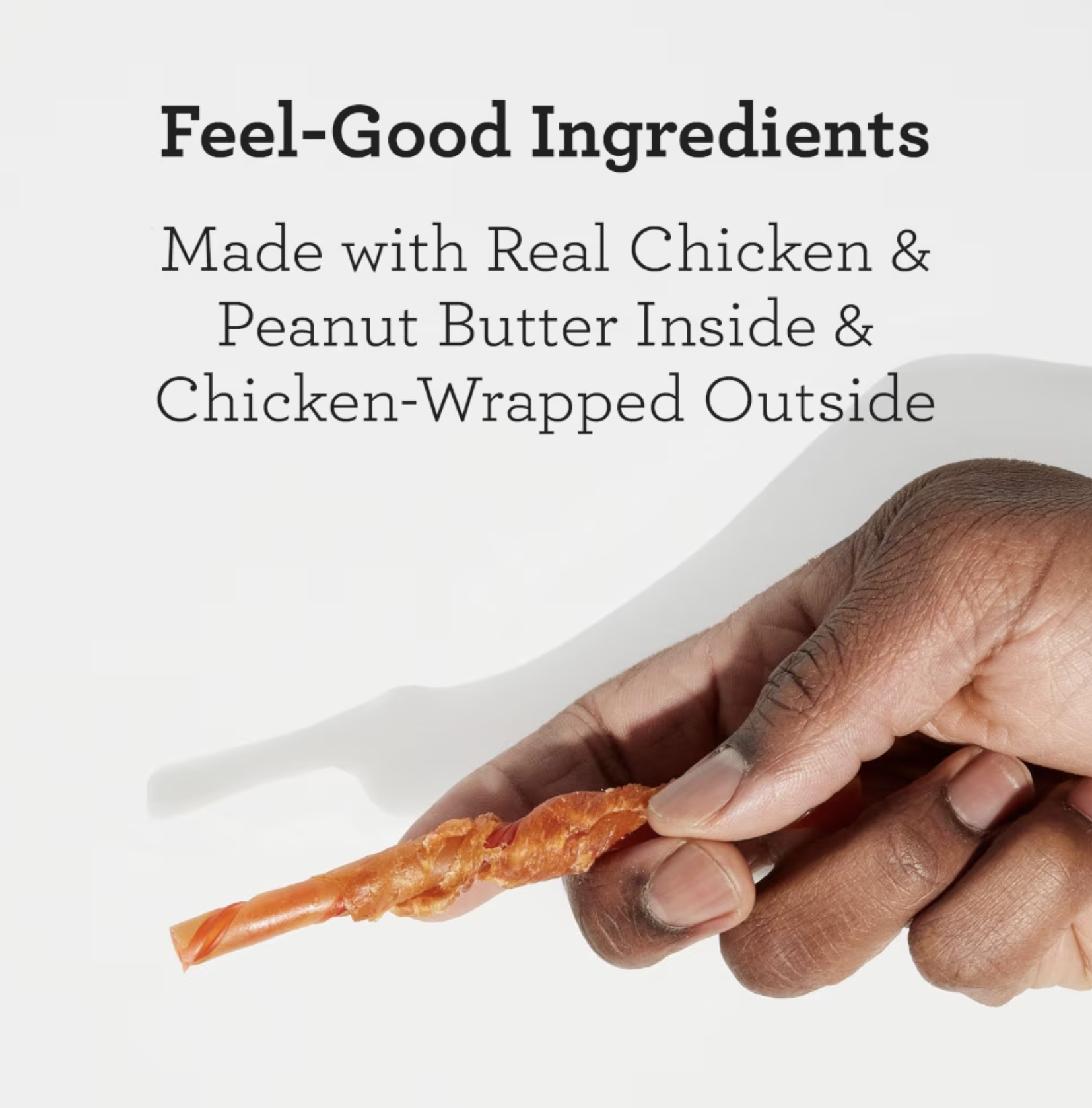 A single DreamBone Twist held between fingers showing the chicken-wrapped outer layer
